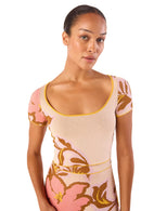 Model wearing a floral dress with pink and gold design on a white background