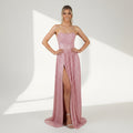 Woman wearing a pink strapless gown with a high slit on a gray background, branded 'Studio MinC'.