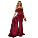 Woman in a burgundy evening gown holding a clutch in a dimly lit room.